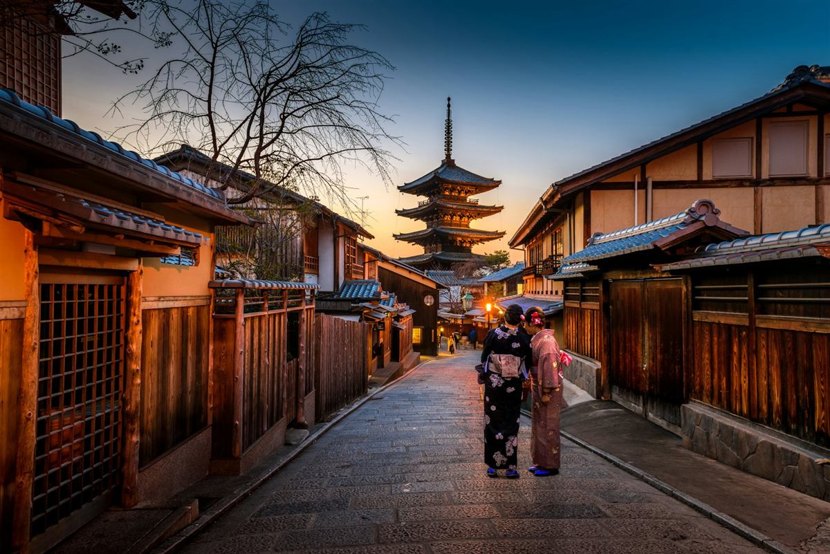 Twilight street in Kyoto with a wooden pagoda and people in kimono