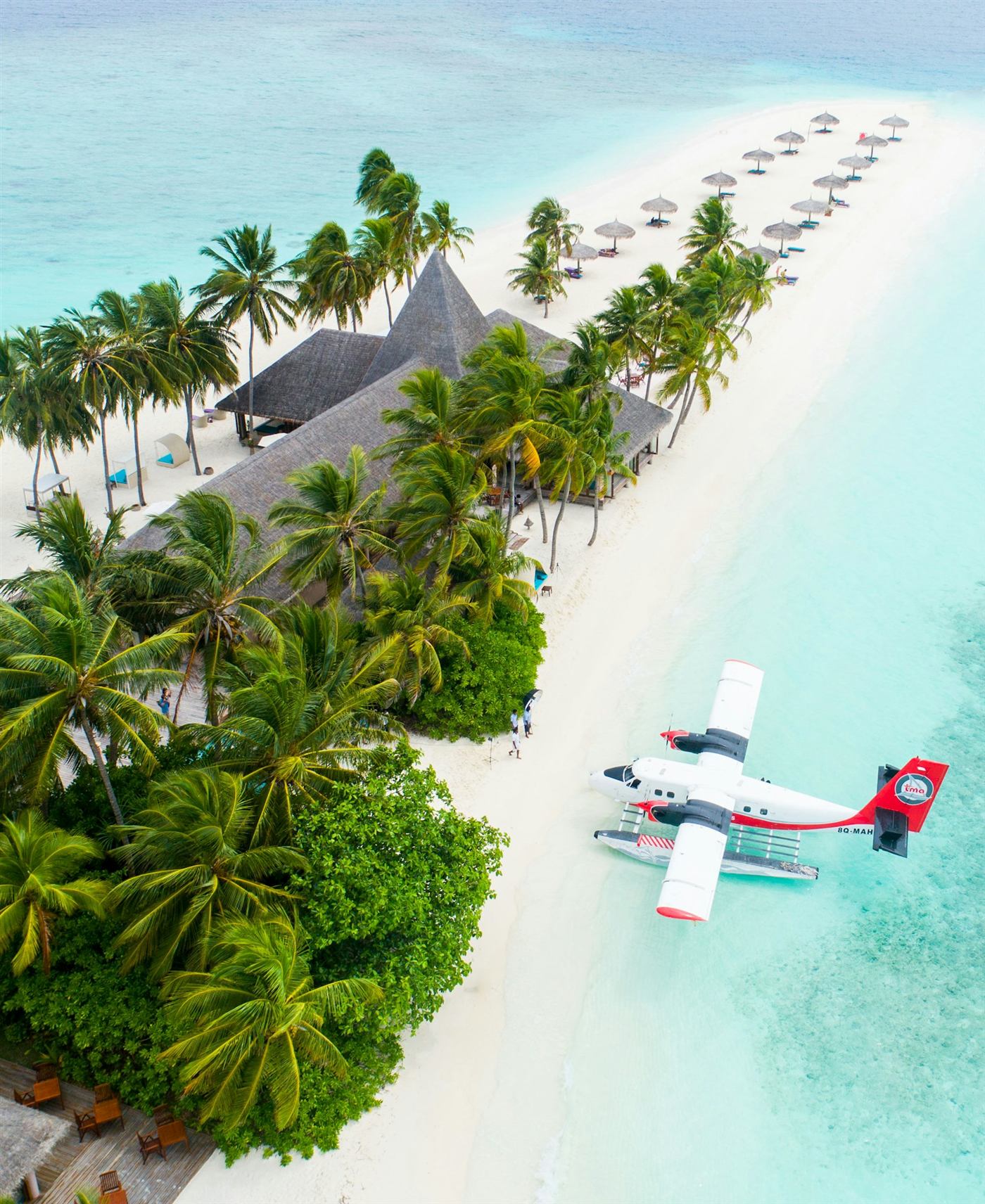 White-sand island with palm trees, turquoise lagoon and a seaplane in the Maldives