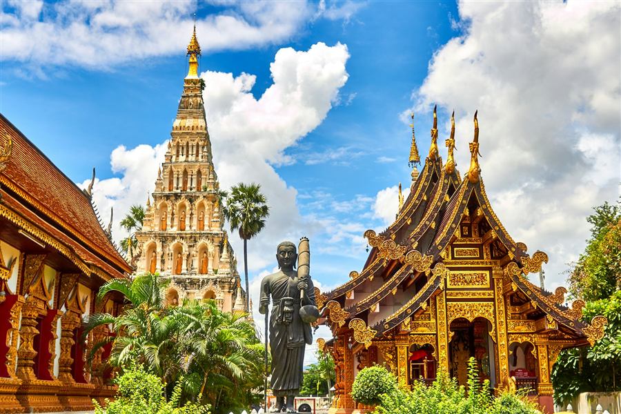 Ornate golden temple spires against a bright blue sky in Thailand