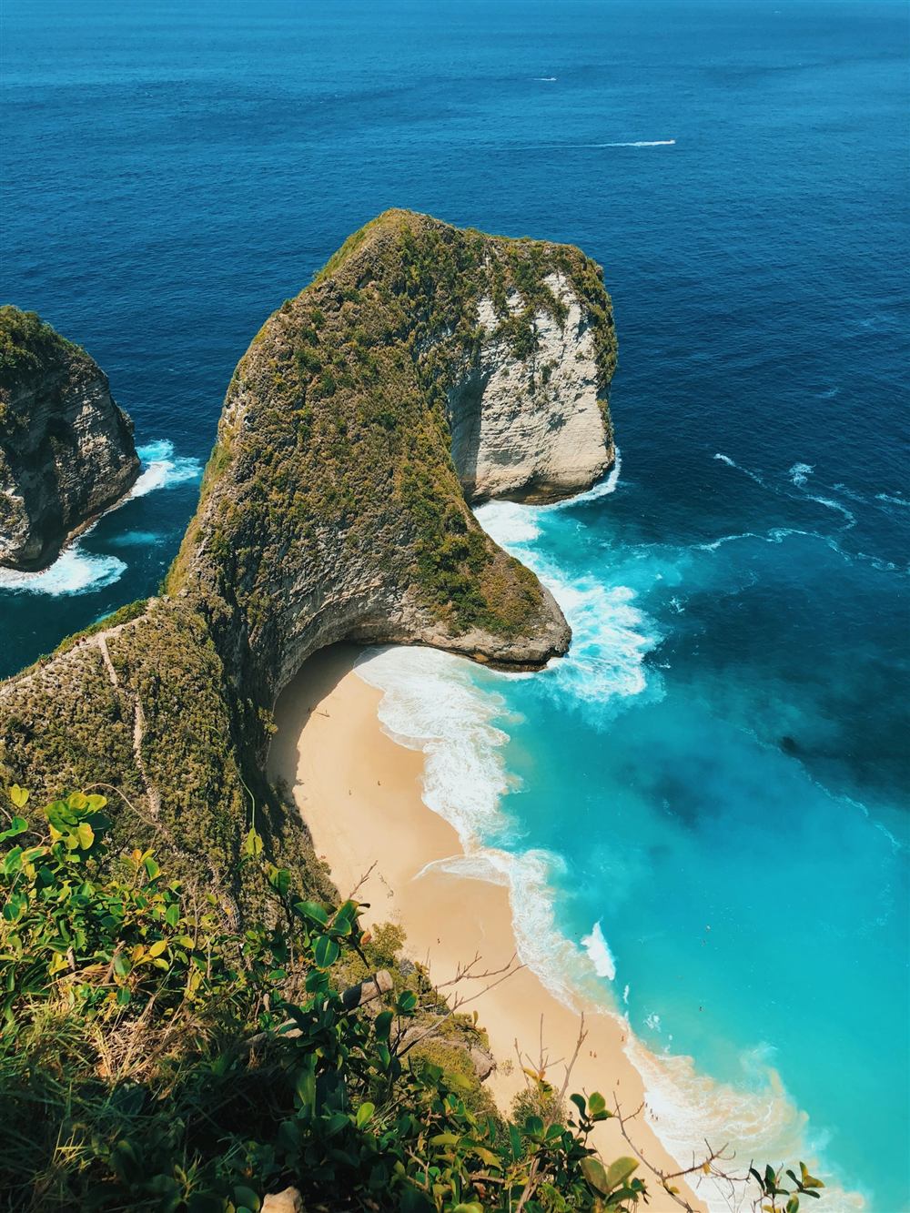 Turquoise cove and jagged green cliffs on Nusa Penida island