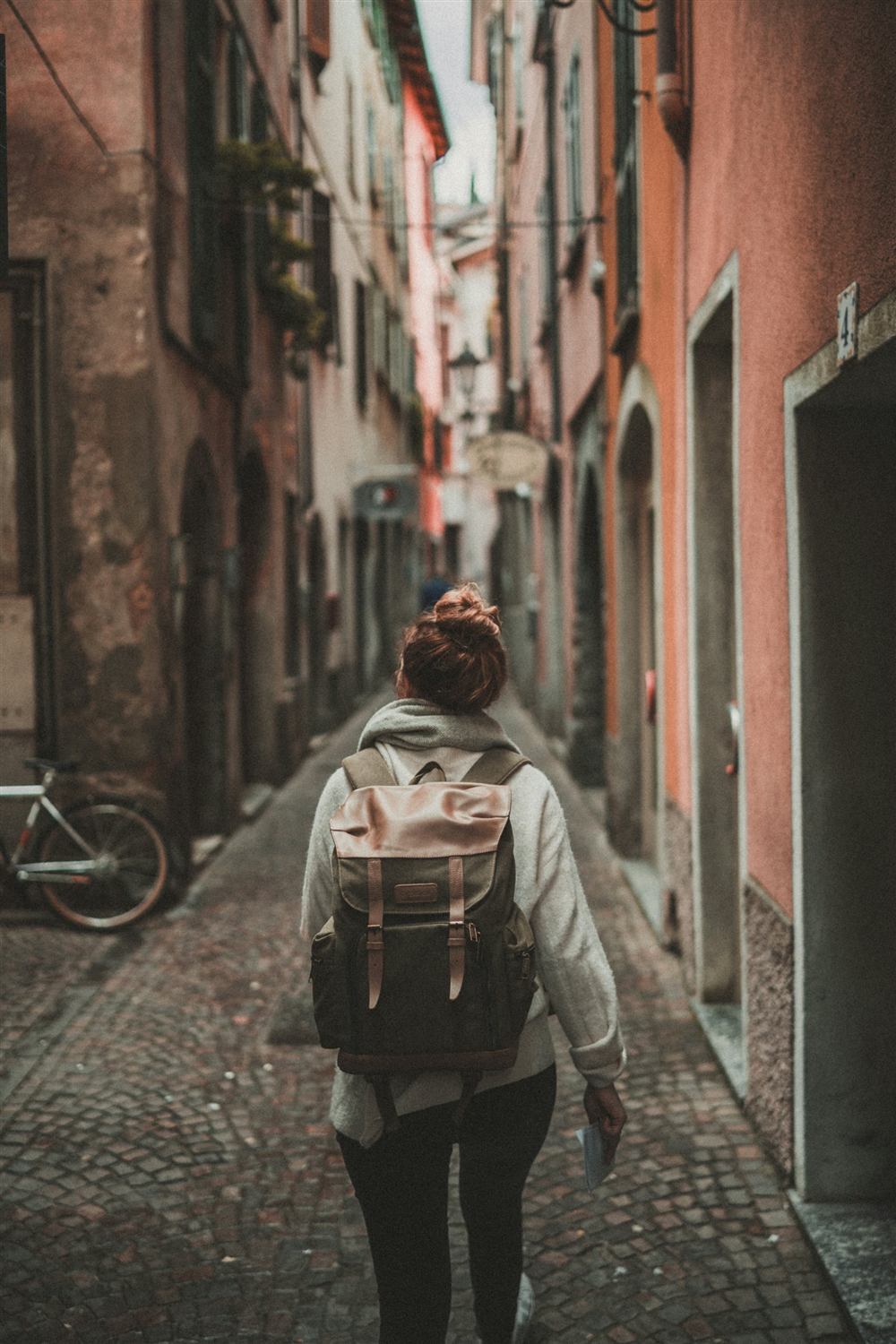 A solo traveler with a backpack walking through a cobbled old-town street