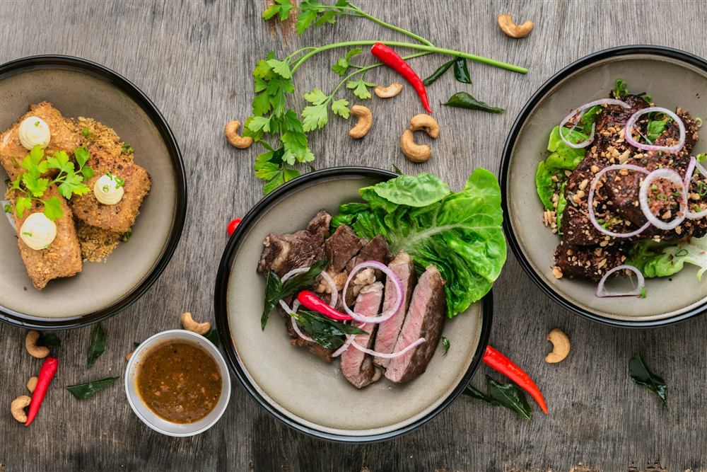 Overhead view of colourful Thai dishes on a rustic table