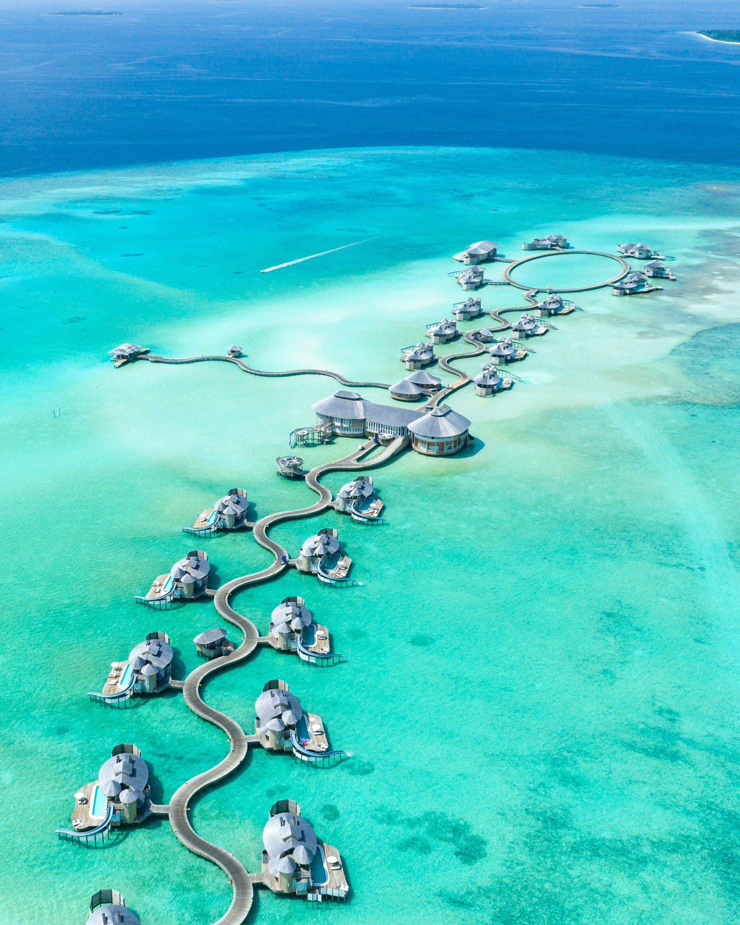 Aerial view of overwater villas linked by a jetty over turquoise Maldivian lagoon