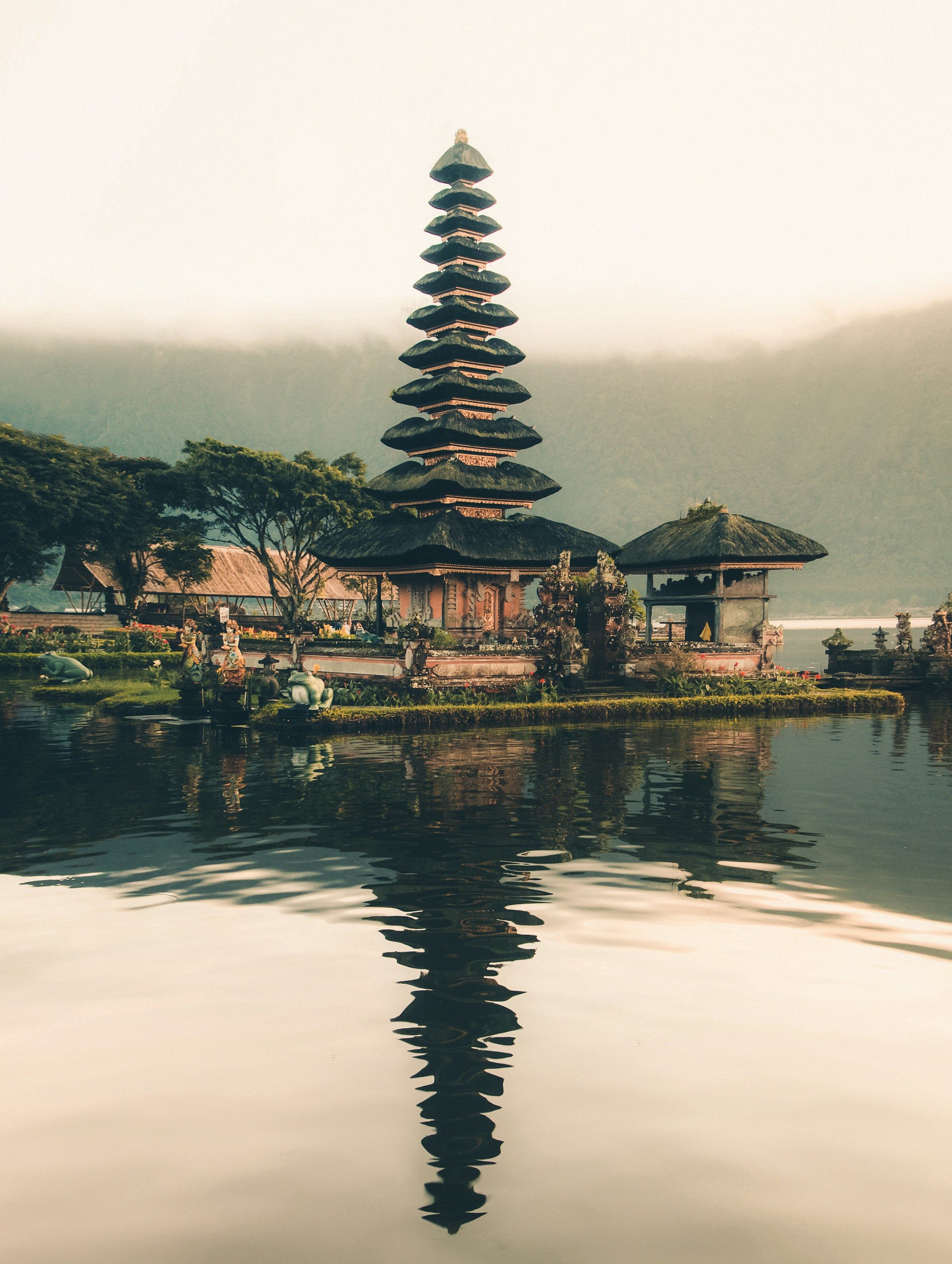 A Balinese water temple reflected in a still lake at golden hour